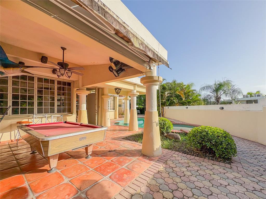 A covered patio features a pool table, tiled flooring, and a view of a swimming pool — 21 PQUE. TIVOLI | PASEO DEL PARQUE, SAN JUAN, PR