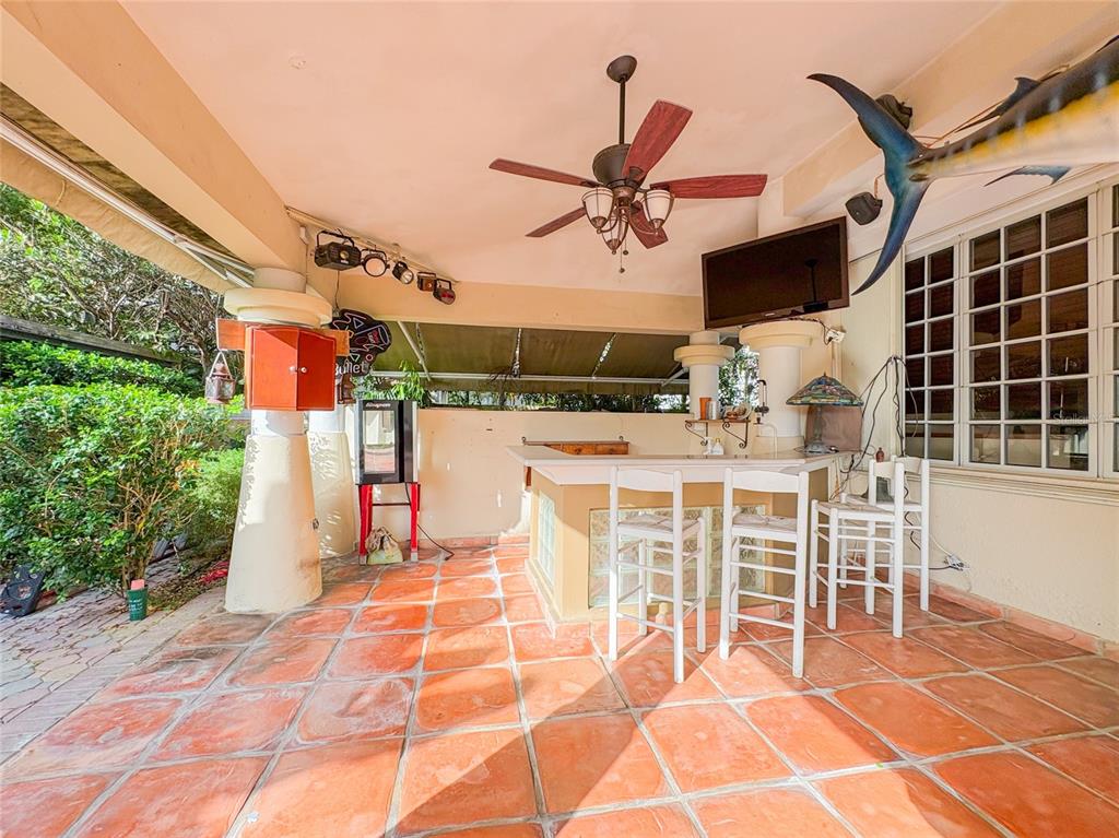 An outdoor patio features a bar with white chairs, a ceiling fan, and tiled flooring — 21 PQUE. TIVOLI | PASEO DEL PARQUE, SAN JUAN, PR