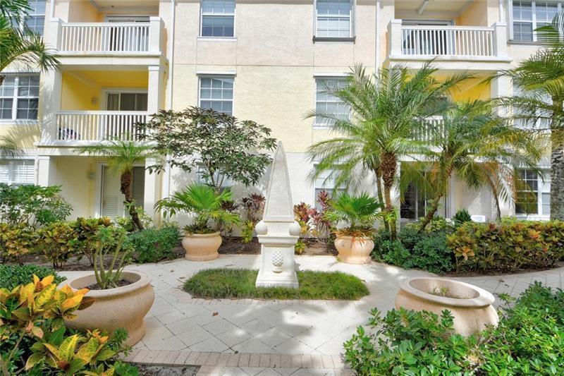 A stone obelisk stands in a paved courtyard surrounded by potted plants and apartment balconies — 275 Murcia Drive # 208, Jupiter FL 33458, JUPITER, FL