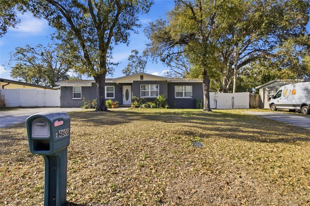 A single-story gray house with a front lawn, large trees, and a mailbox — 4608 HARVEY AVENUE, TAMPA, FL
