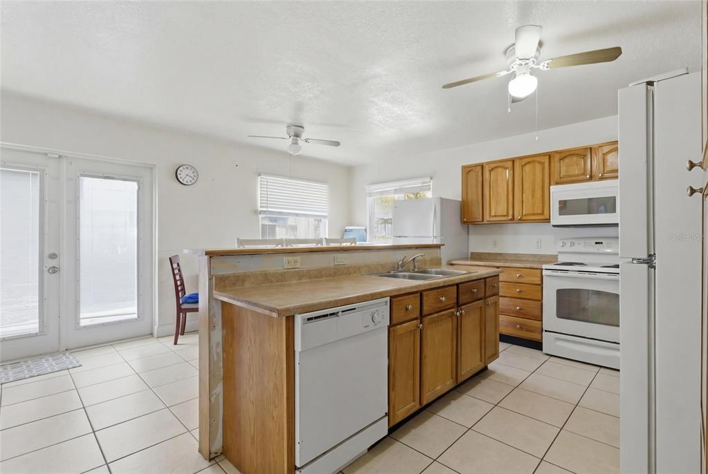 A kitchen with wood cabinets, white appliances, tile floors, and a breakfast bar island — 4608 HARVEY AVENUE, TAMPA, FL