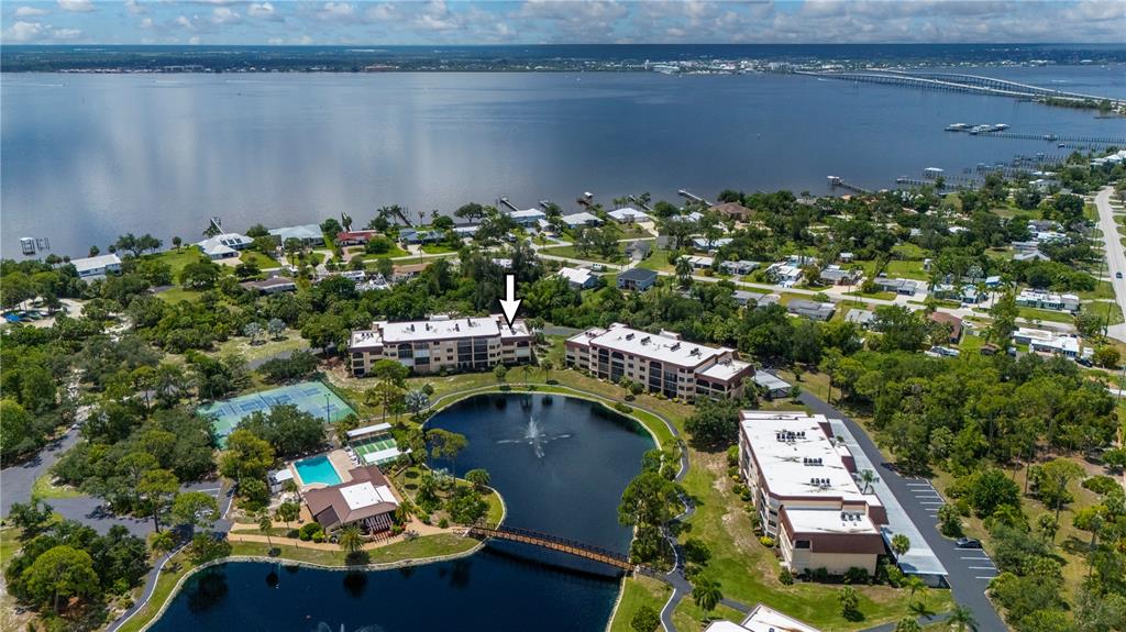An aerial view shows apartment buildings, a pond with a fountain, and a bridge — 23465 HARBORVIEW ROAD UNIT 631, PUNTA GORDA, FL