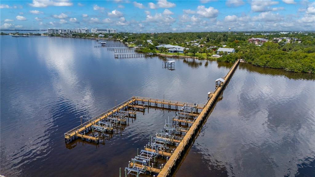 An aerial view shows a long wooden dock with multiple boat lifts extending into a bay — 23465 HARBORVIEW ROAD UNIT 631, PUNTA GORDA, FL