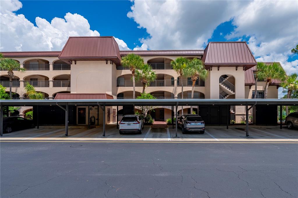 A multi-story apartment building features a covered parking area with several parked vehicles — 23465 HARBORVIEW ROAD UNIT 631, PUNTA GORDA, FL