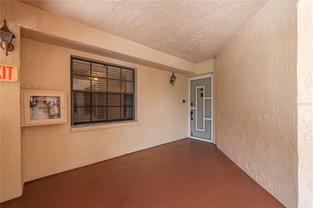 A covered entryway features a red floor, a window with dark shutters, and a white door — 23465 HARBORVIEW ROAD UNIT 631, PUNTA GORDA, FL