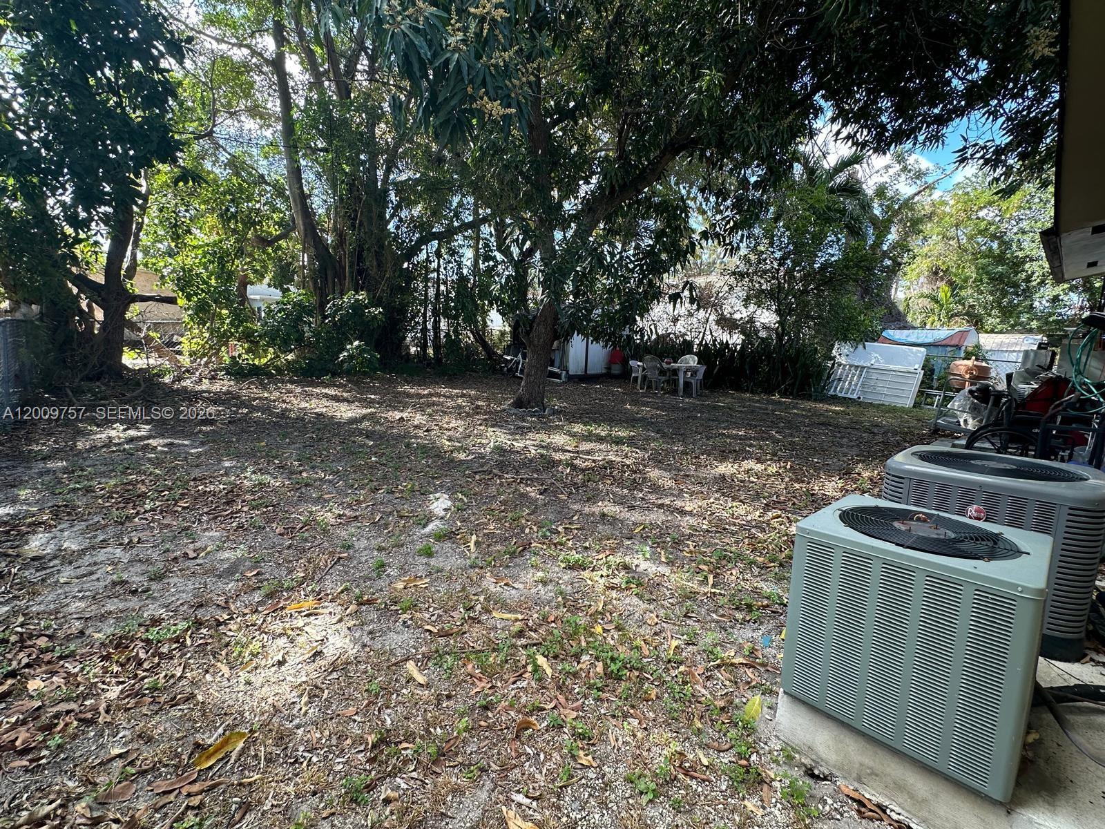 A backyard features a large tree, scattered leaves, and two outdoor air conditioning units — 420 NW 32nd St, Miami FL 33127, MIAMI, FL