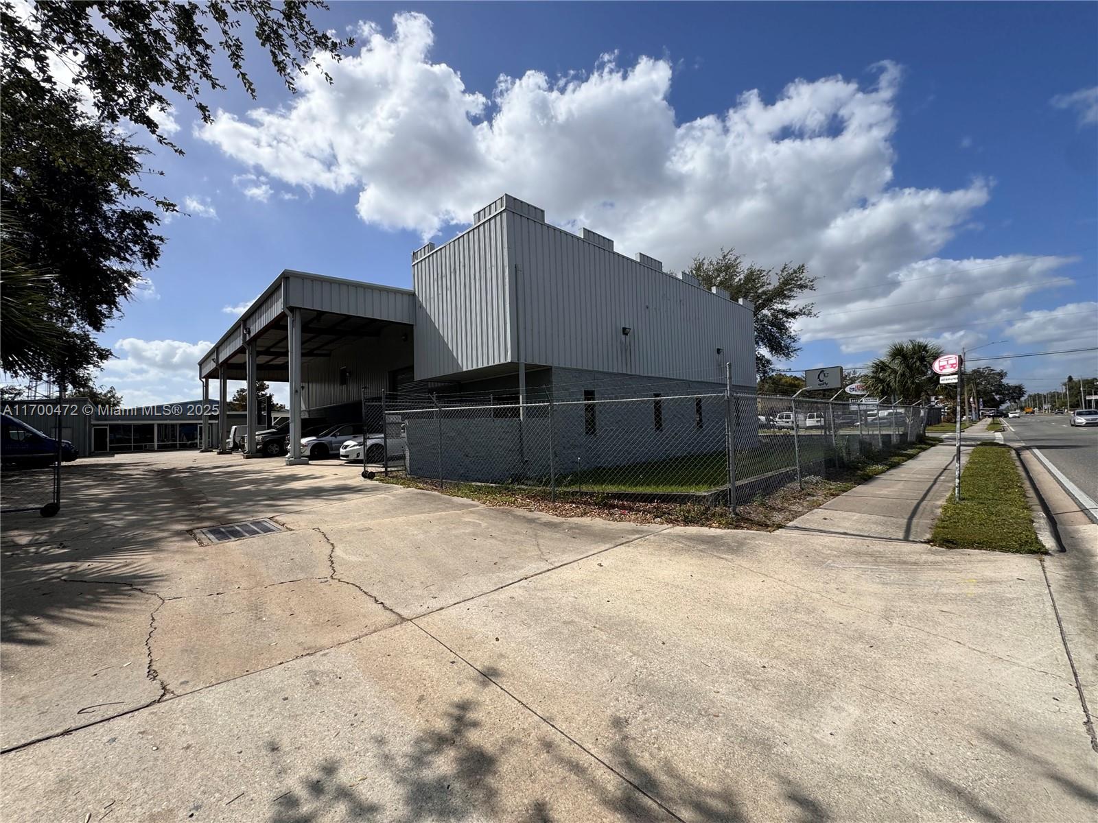 A gray industrial building with a covered parking area is enclosed by a chain-link fence — 5909 Anno Ave # 5909, Orlando FL 32809, ORLANDO, FL