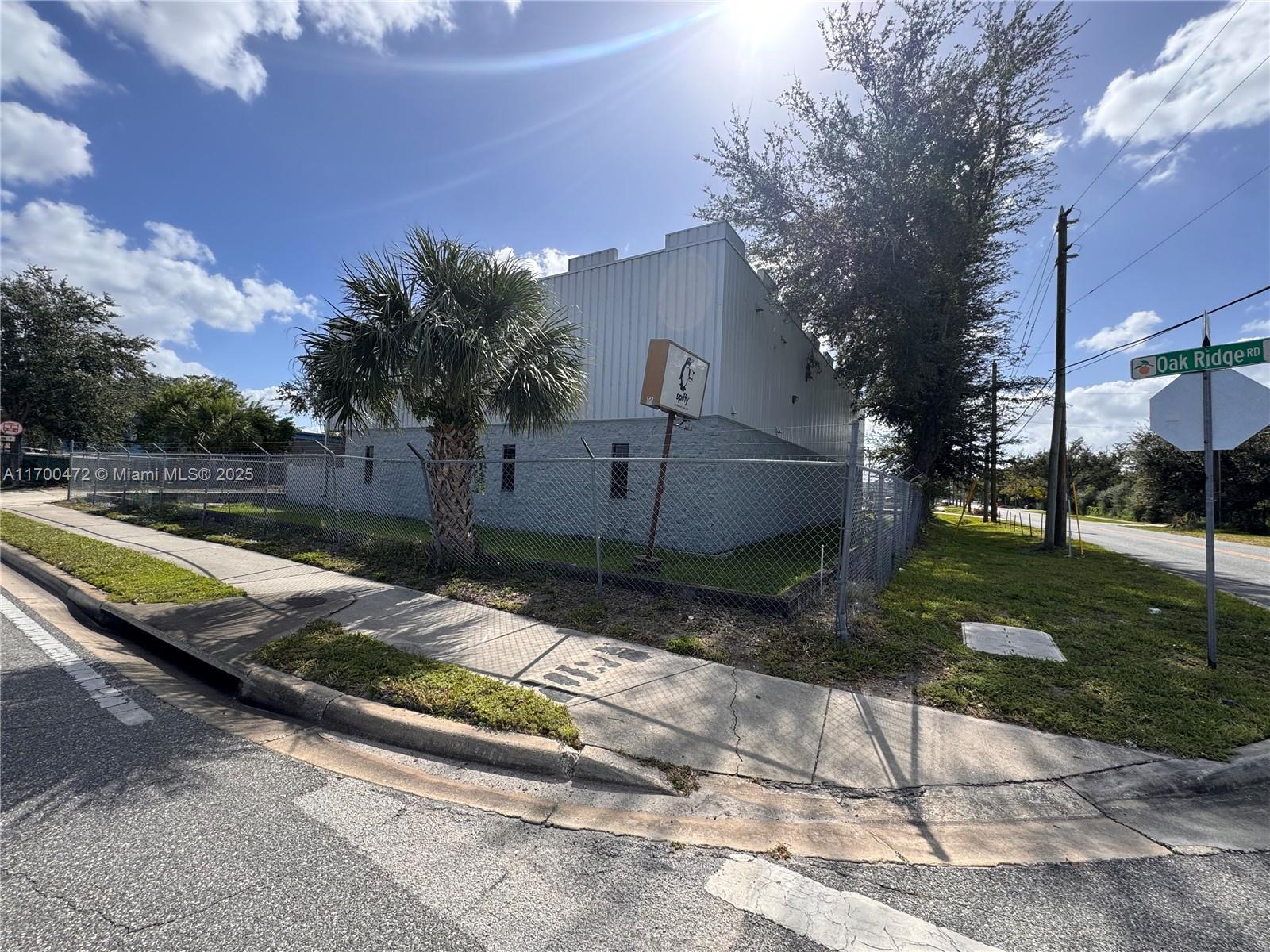 A fenced commercial building stands at a street corner with a palm tree and sign — 5909 Anno Ave # 5909, Orlando FL 32809, ORLANDO, FL