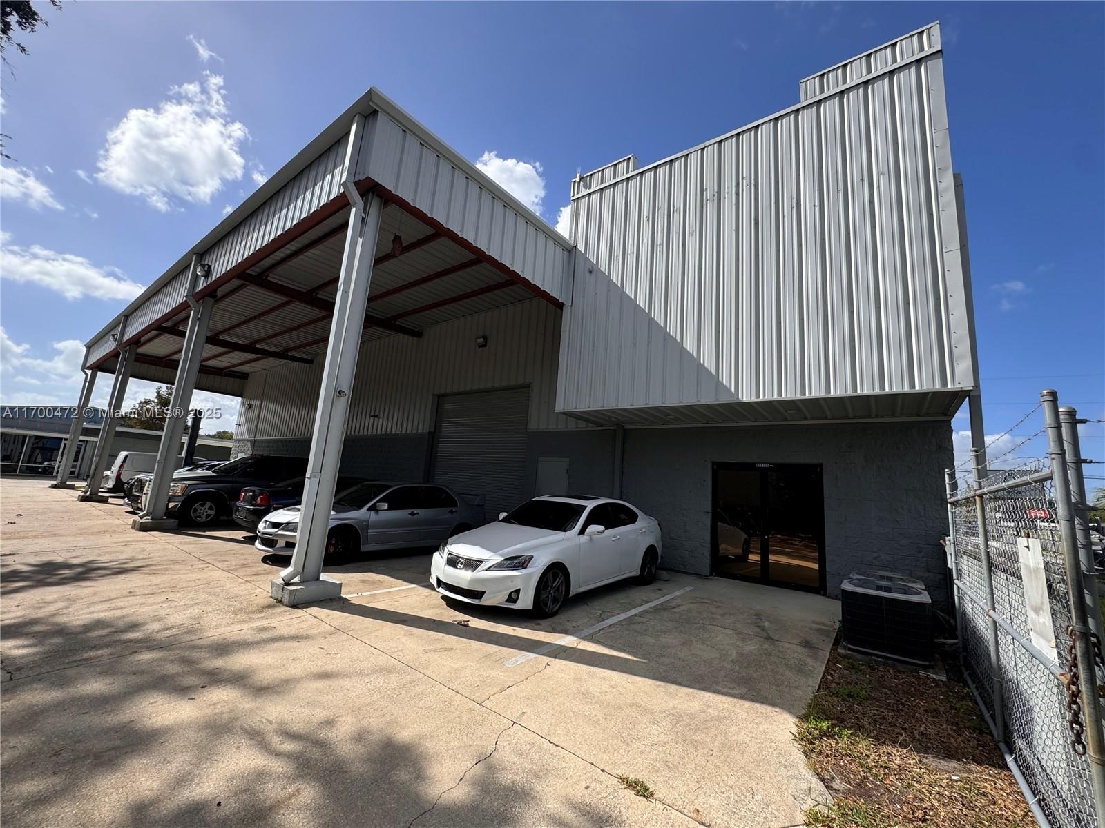 A white Lexus is parked in front of a metal-sided industrial building with a covered bay — 5909 Anno Ave # 5909, Orlando FL 32809, ORLANDO, FL