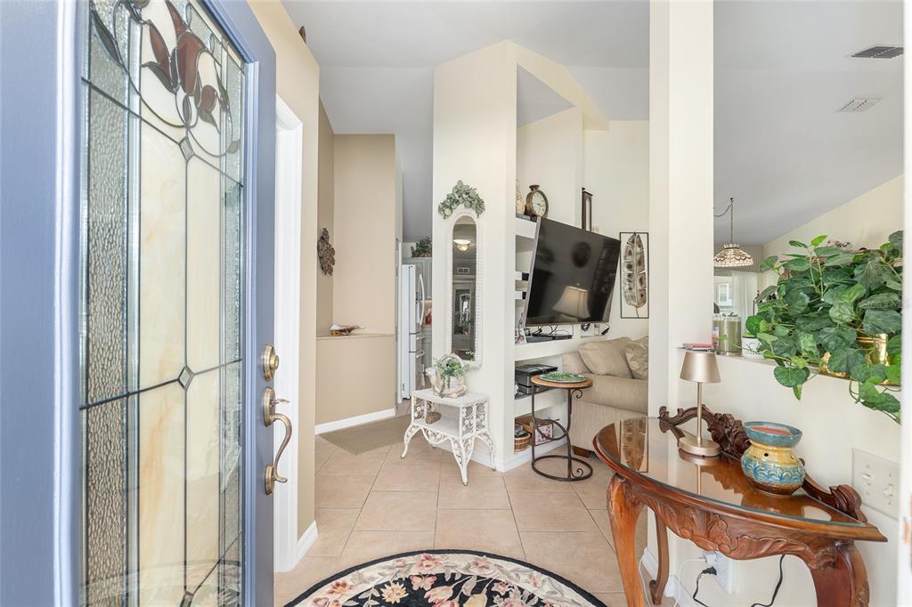 An entryway with tile flooring, a decorative glass door, and a view into the living room — 17380 SE 111TH COURT, SUMMERFIELD, FL