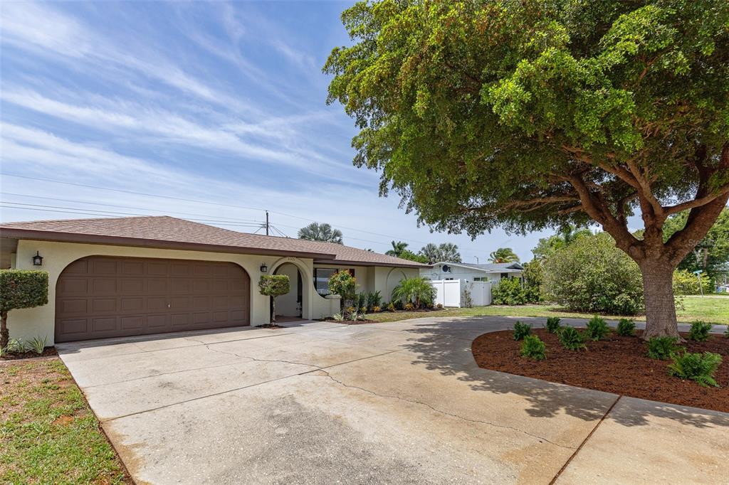 A single-story house with a brown garage door and a large tree in the yard — 4005 17TH AVENUE W, BRADENTON, FL