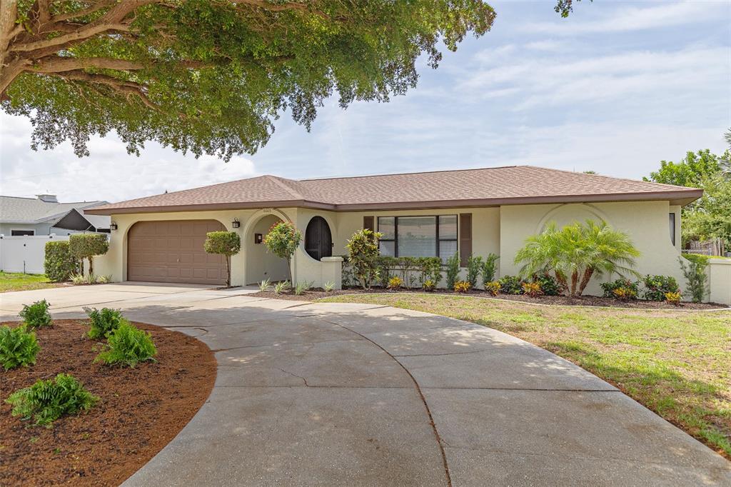 A single-story house with a brown garage door, arched entryway, and a curved concrete driveway — 4005 17TH AVENUE W, BRADENTON, FL
