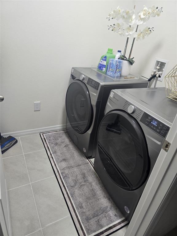 A laundry room features grey front-loading appliances, a runner rug, and tile flooring — 3045 TOBAGO DRIVE, HAINES CITY, FL