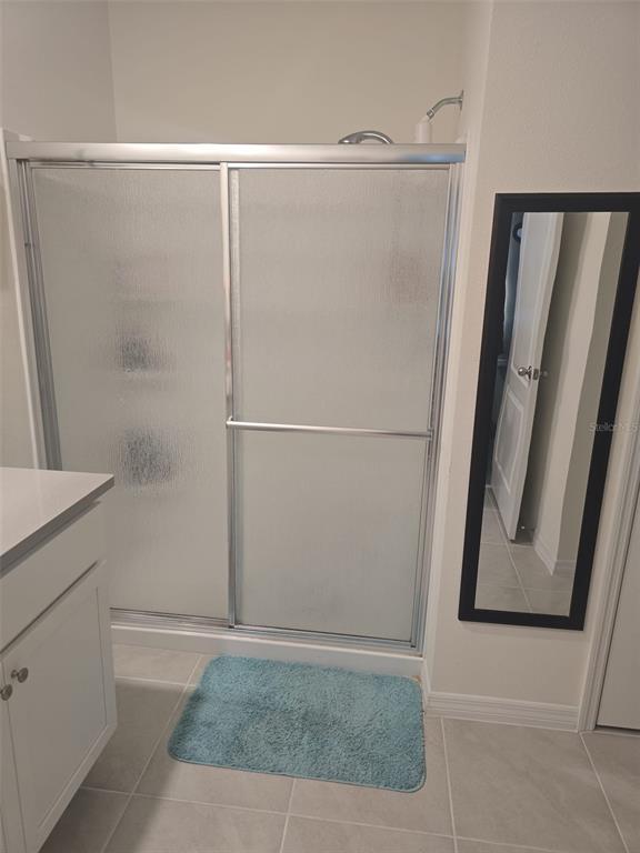 A bathroom features a glass-enclosed shower, a white vanity, and a wall-mounted mirror — 3045 TOBAGO DRIVE, HAINES CITY, FL