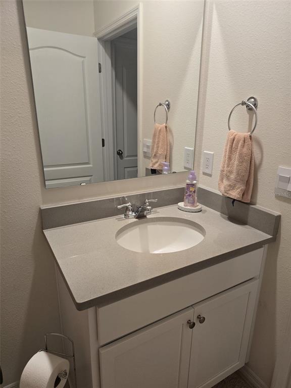 A bathroom vanity with a gray countertop, white cabinets, a mirror, and a towel ring — 3045 TOBAGO DRIVE, HAINES CITY, FL