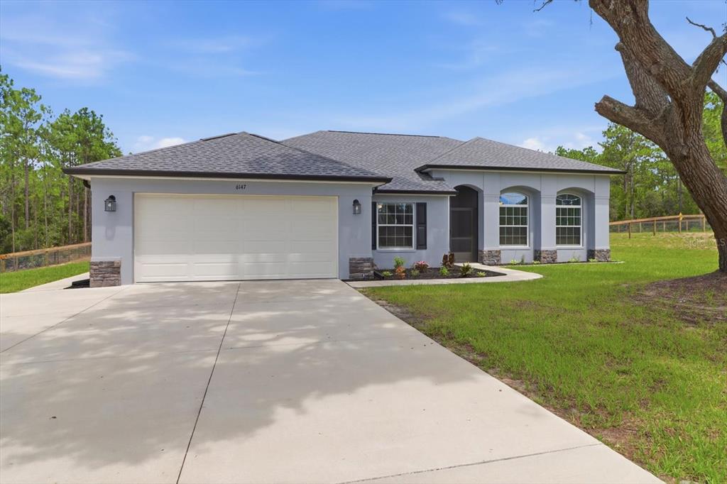 A single-story house with a two-car garage and a concrete driveway sits on a lawn — 6147 W SETTLER DRIVE, BEVERLY HILLS, FL