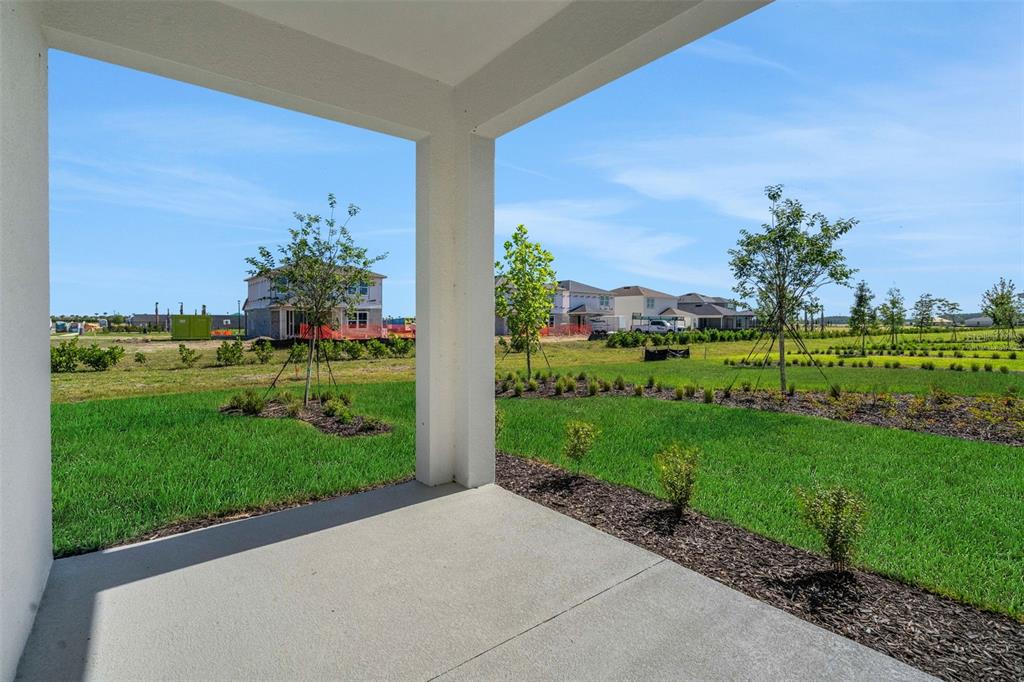 A covered concrete patio overlooks a grassy backyard with young trees and neighboring houses — 16928 COTTONTAIL CIRCLE, PUNTA GORDA, FL