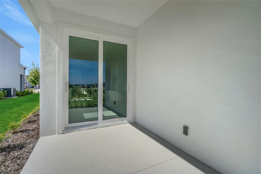A concrete patio features a white sliding glass door and a plain exterior wall — 16928 COTTONTAIL CIRCLE, PUNTA GORDA, FL