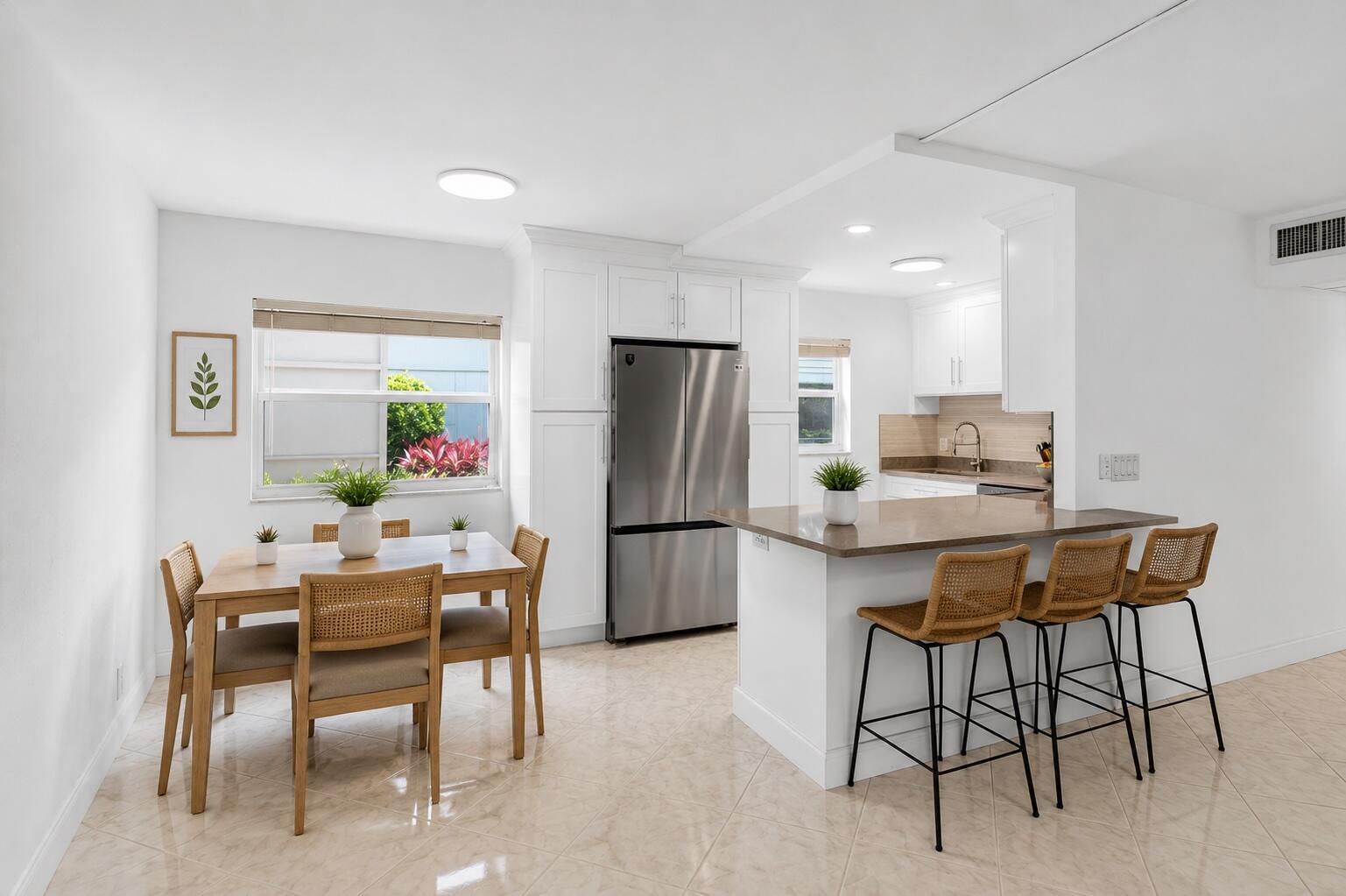 A bright kitchen and dining area with white cabinets, stainless appliances, and tile flooring — 160 Tuscany C, Delray Beach FL 33446, DELRAY BEACH, FL