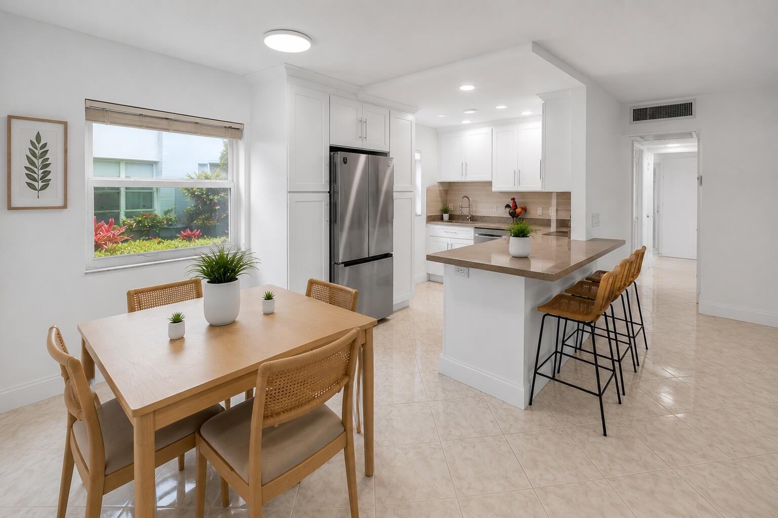 A bright kitchen and dining area features white cabinetry, stainless steel appliances, and tile flooring — 160 Tuscany C, Delray Beach FL 33446, DELRAY BEACH, FL