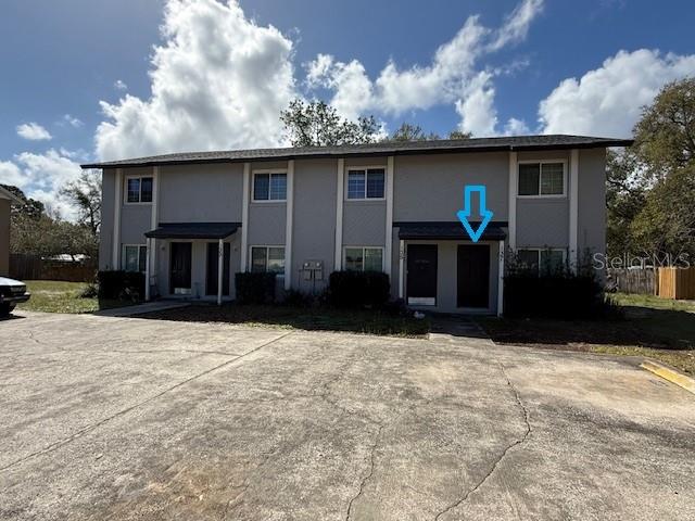 A two-story apartment building with a blue arrow pointing to a ground-floor entrance — 137 GARDEN DRIVE, WINTER SPRINGS, FL