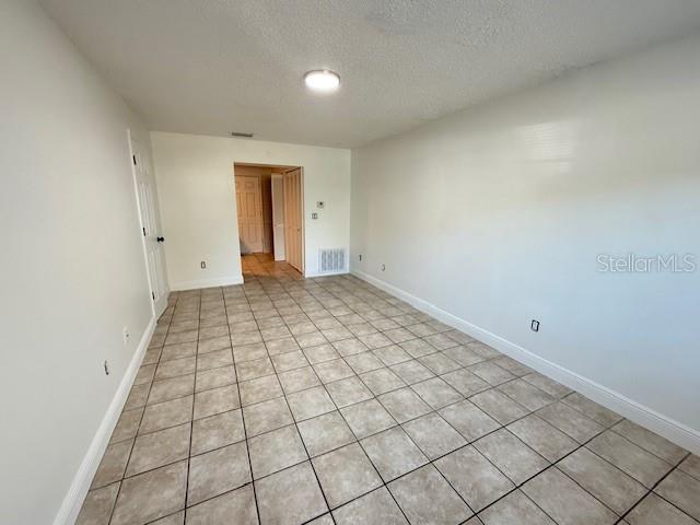 An empty room features light-colored tile flooring, white walls, and a single ceiling light fixture — 137 GARDEN DRIVE, WINTER SPRINGS, FL