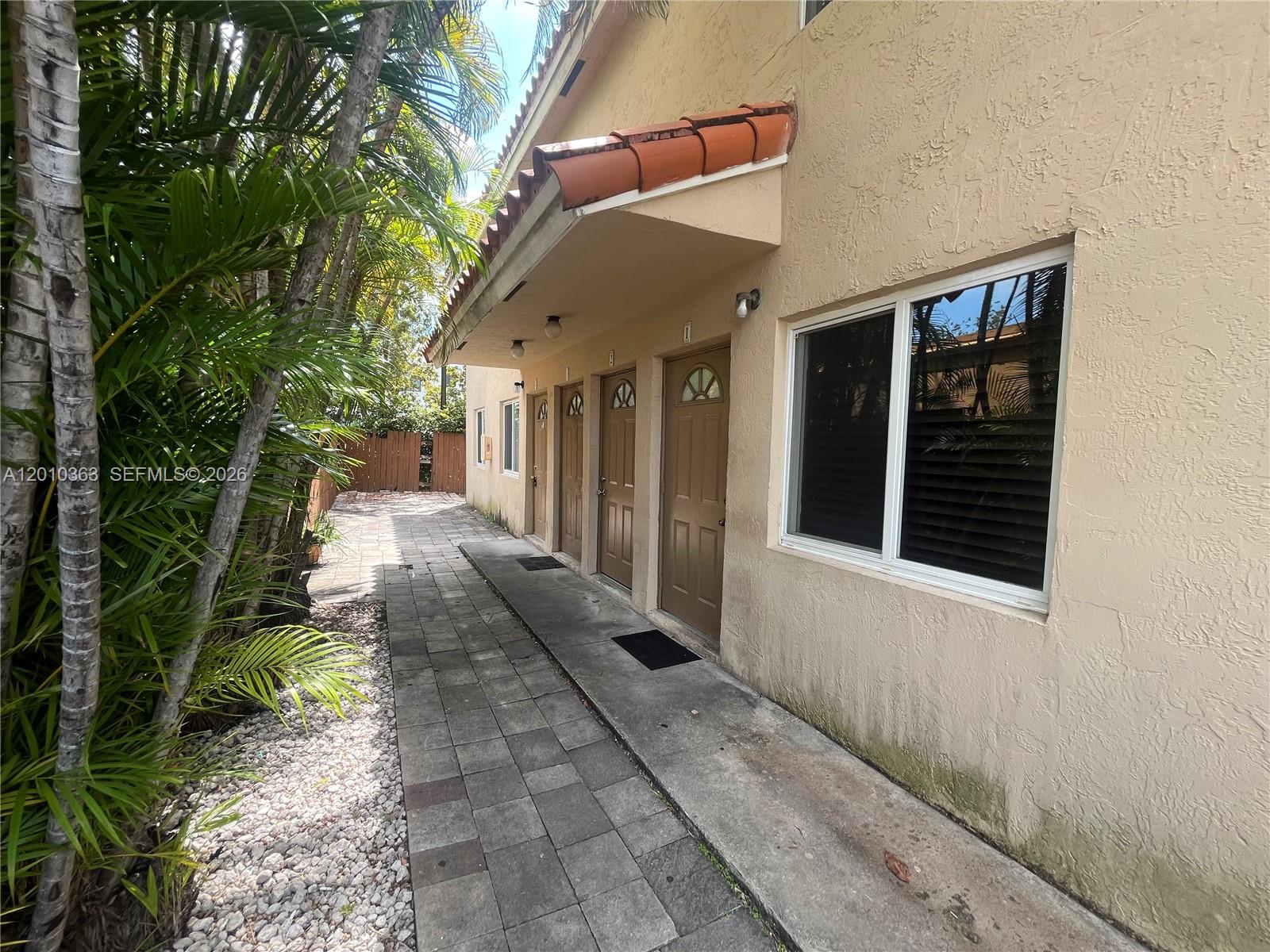 A paved walkway leads past several brown doors along the side of a stucco building — 1419 SW 22nd Ave # 4, Miami FL 33145, MIAMI, FL