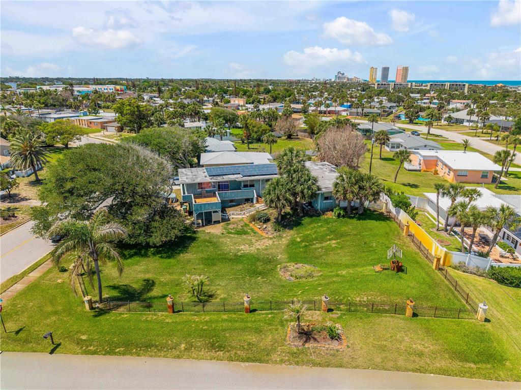 An aerial view shows a house with solar panels on a large, fenced grassy lot — 401 DRIFTWOOD AVENUE, DAYTONA BEACH, FL