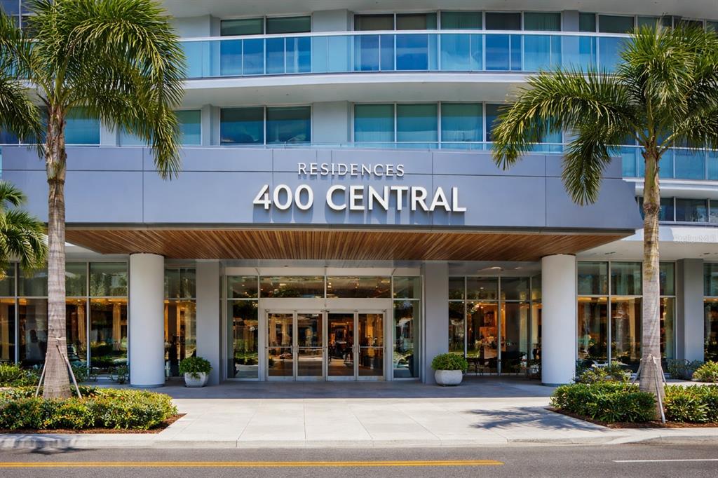 The exterior entrance of a modern residential building features glass doors and palm trees — 400 CENTRAL AVENUE UNIT 2603, ST PETERSBURG, FL