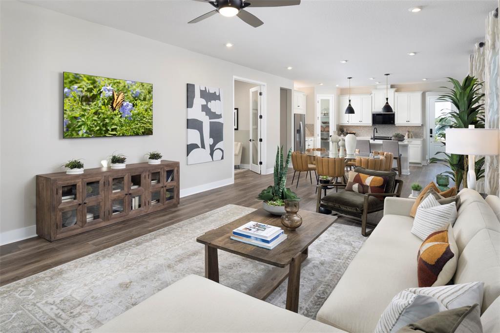 A living room with a wooden console, coffee table, sofa, and an open-concept kitchen — 11187 LIVEWELL COURT, VENICE, FL