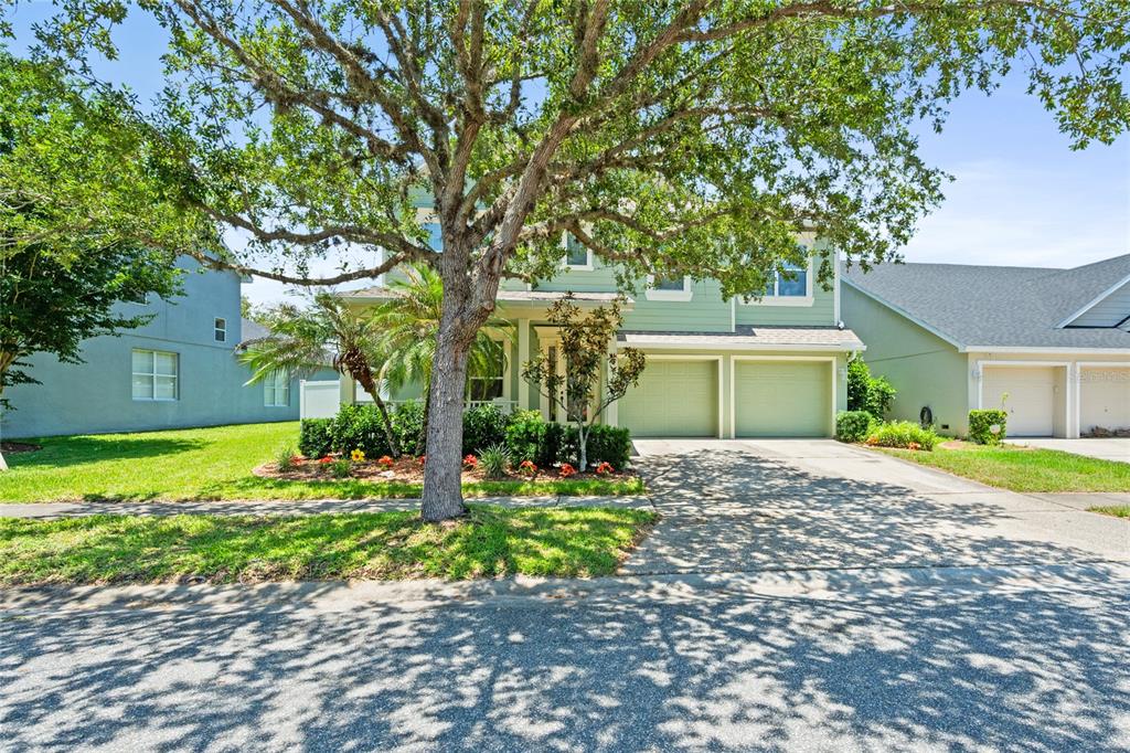 A two-story light green house with a two-car garage and a large front tree — 4930 ATWOOD DRIVE, ORLANDO, FL