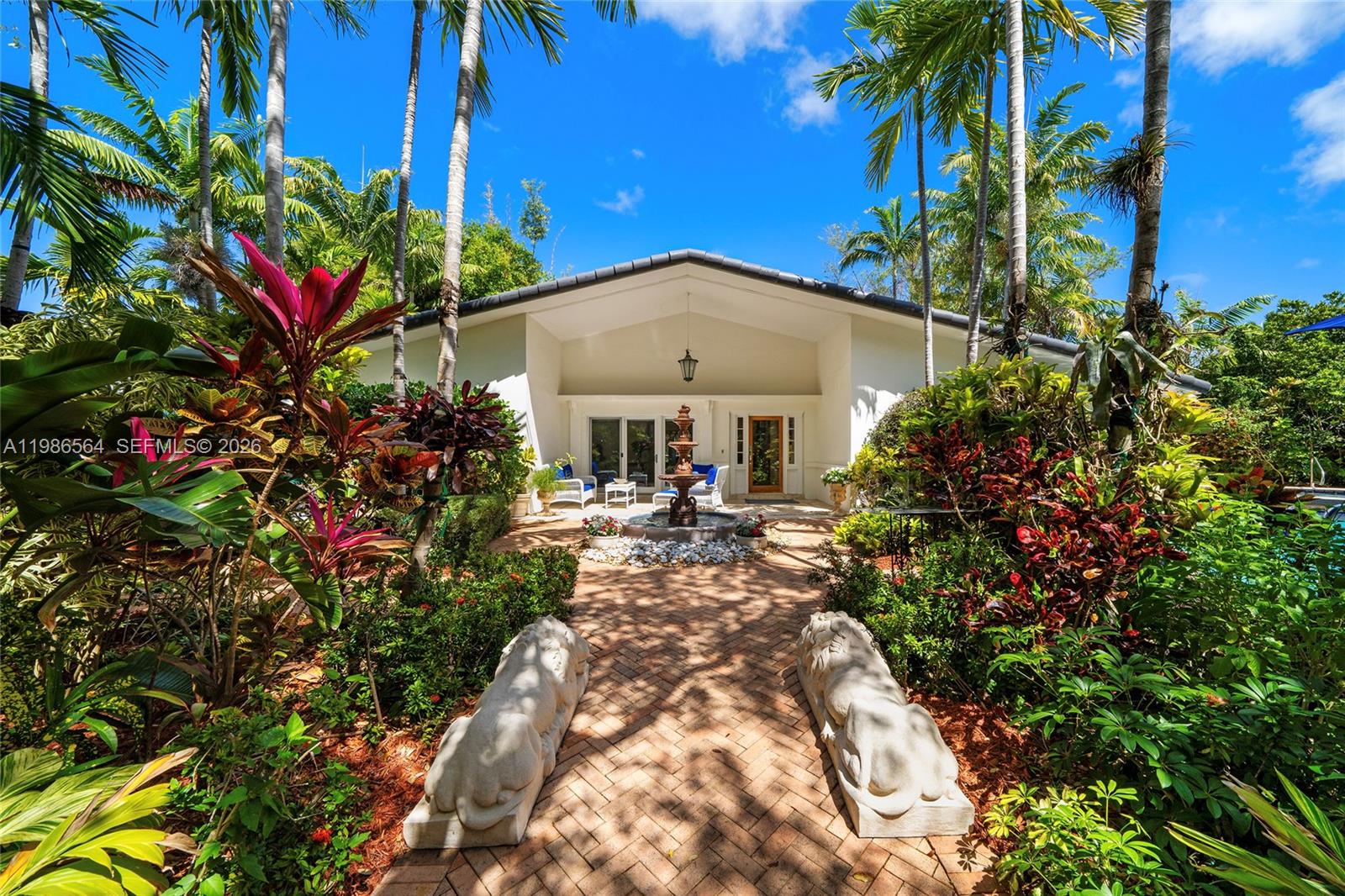 A brick walkway leads past two stone lion statues to a fountain and house entrance — 269 Cranwood Dr, Key Biscayne FL 33149, KEY BISCAYNE, FL