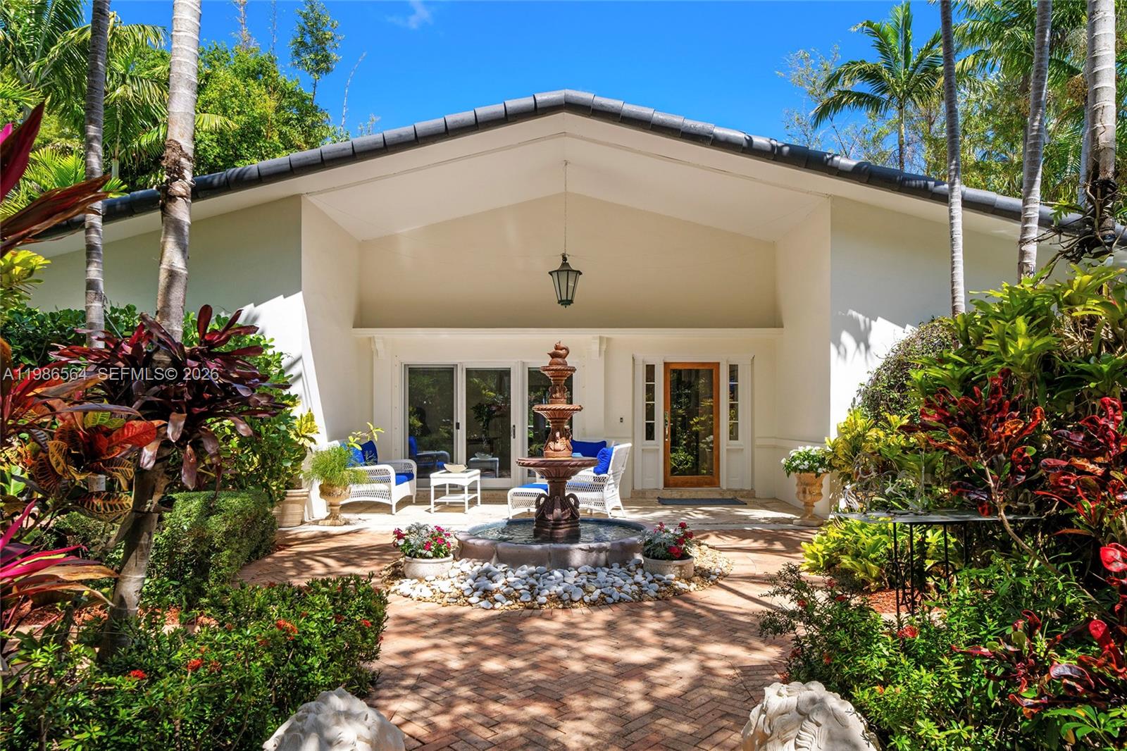 A stone fountain sits in the center of a brick patio in front of a house — 269 Cranwood Dr, Key Biscayne FL 33149, KEY BISCAYNE, FL