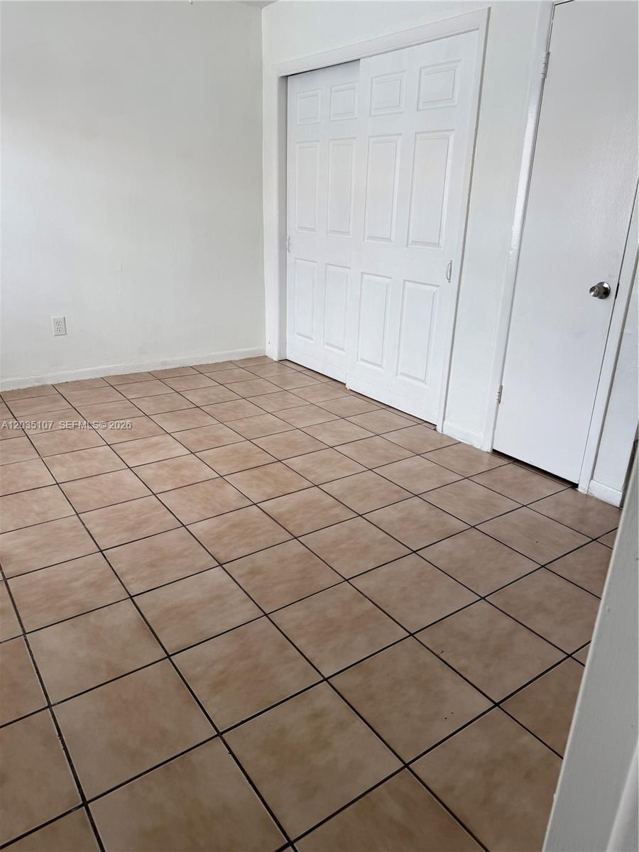 A room with beige tile flooring, white walls, and two sets of white closet doors — 166 W 8th St # 3, Hialeah FL 33010, HIALEAH, FL