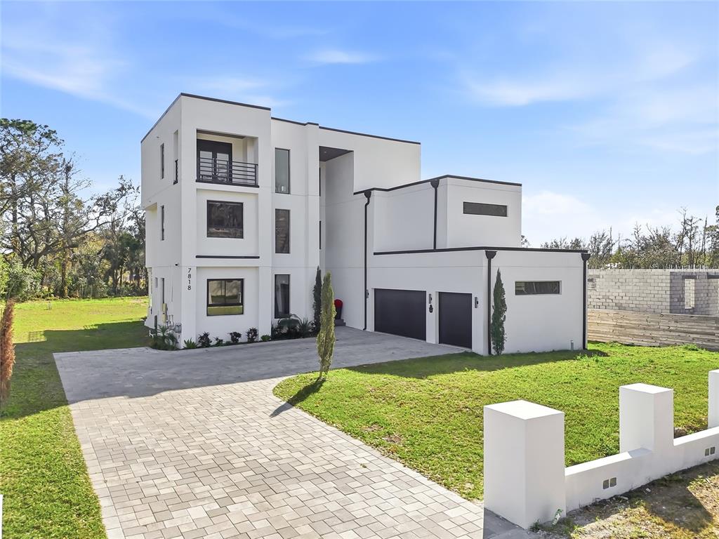 A modern three-story white house with a two-car garage and a paved driveway — 7818 N HUBERT AVENUE, TAMPA, FL