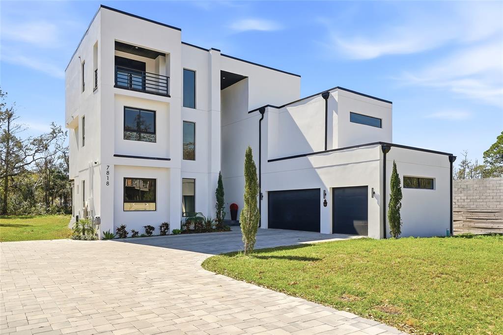 A modern three-story white house with a two-car garage and a paved driveway — 7818 N HUBERT AVENUE, TAMPA, FL