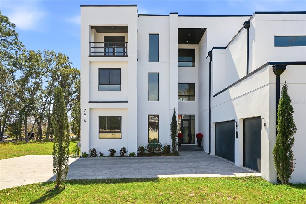 A modern three-story white house features a balcony, large windows, and a two-car garage — 7818 N HUBERT AVENUE, TAMPA, FL