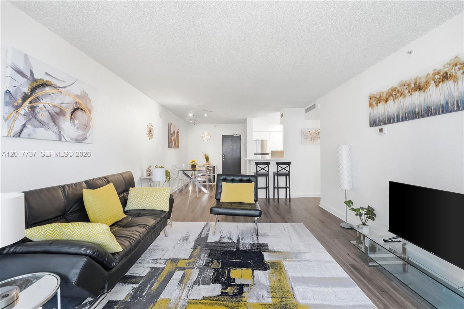 A living room features a black leather sofa, a patterned rug, and a television — 1500 Bay Rd # 666S, Miami Beach FL 33139, MIAMI BEACH, FL