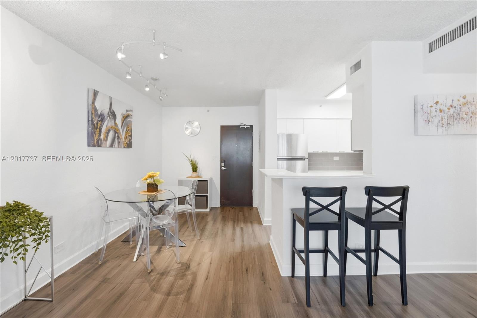 A dining area with a glass table and kitchen breakfast bar with two stools — 1500 Bay Rd # 666S, Miami Beach FL 33139, MIAMI BEACH, FL