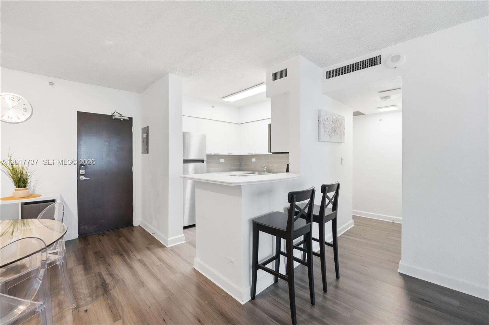 A kitchen with white cabinets and a breakfast bar sits next to an entryway — 1500 Bay Rd # 666S, Miami Beach FL 33139, MIAMI BEACH, FL