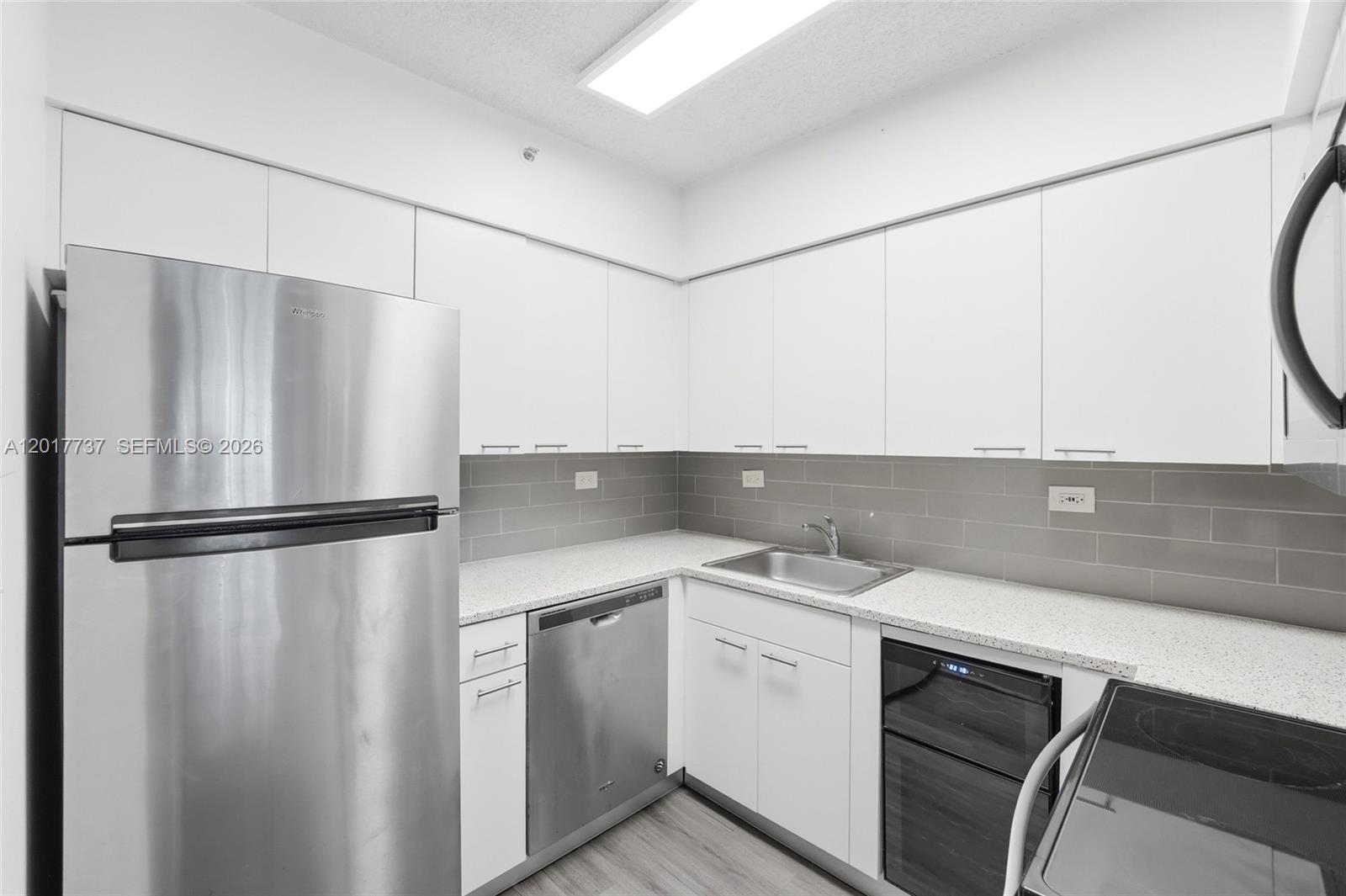 A kitchen features white cabinets, stainless steel appliances, a gray tile backsplash, and light countertops — 1500 Bay Rd # 666S, Miami Beach FL 33139, MIAMI BEACH, FL