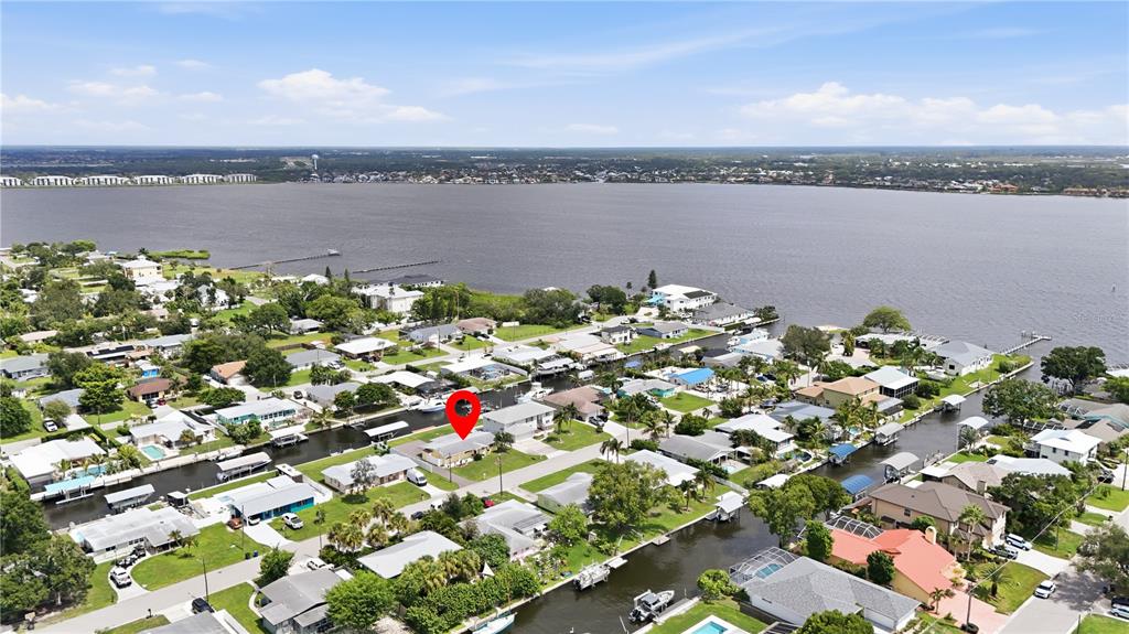An aerial view shows a residential neighborhood with houses situated along a canal and river — 712 POINSETTIA AVENUE, ELLENTON, FL