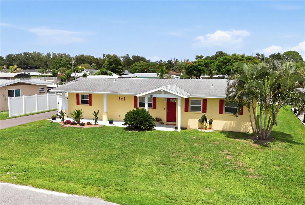 A yellow single-story house with red shutters and a front porch sits on a lawn — 712 POINSETTIA AVENUE, ELLENTON, FL