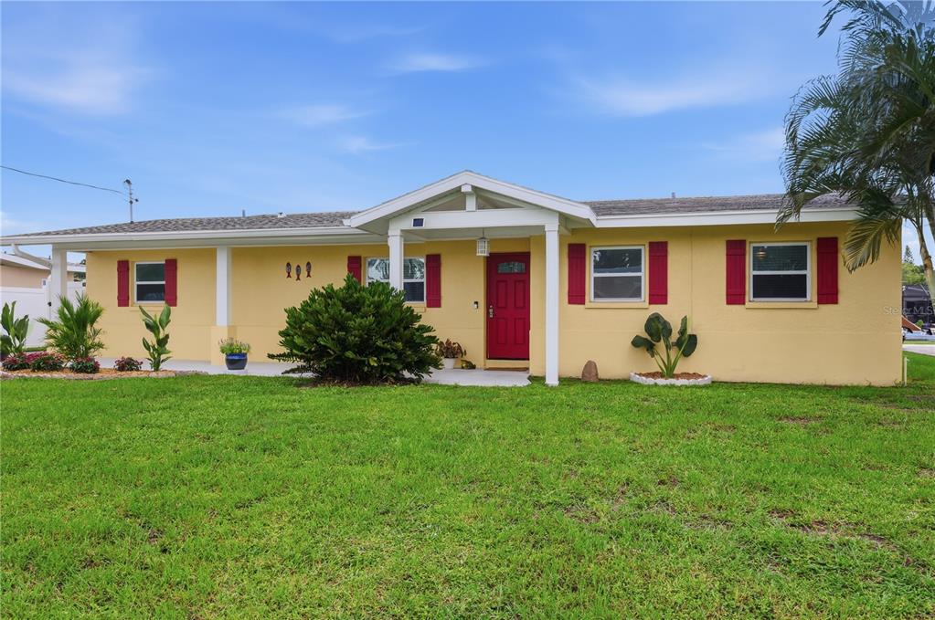 A single-story yellow house with a red front door and red window shutters — 712 POINSETTIA AVENUE, ELLENTON, FL