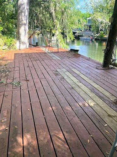 A wooden deck overlooks a canal with a single chair and surrounding trees — 7801 N 12TH STREET, TAMPA, FL