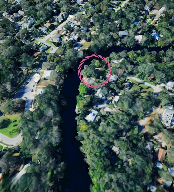 This is an aerial view of a residential neighborhood featuring a canal and dense trees — 7801 N 12TH STREET, TAMPA, FL