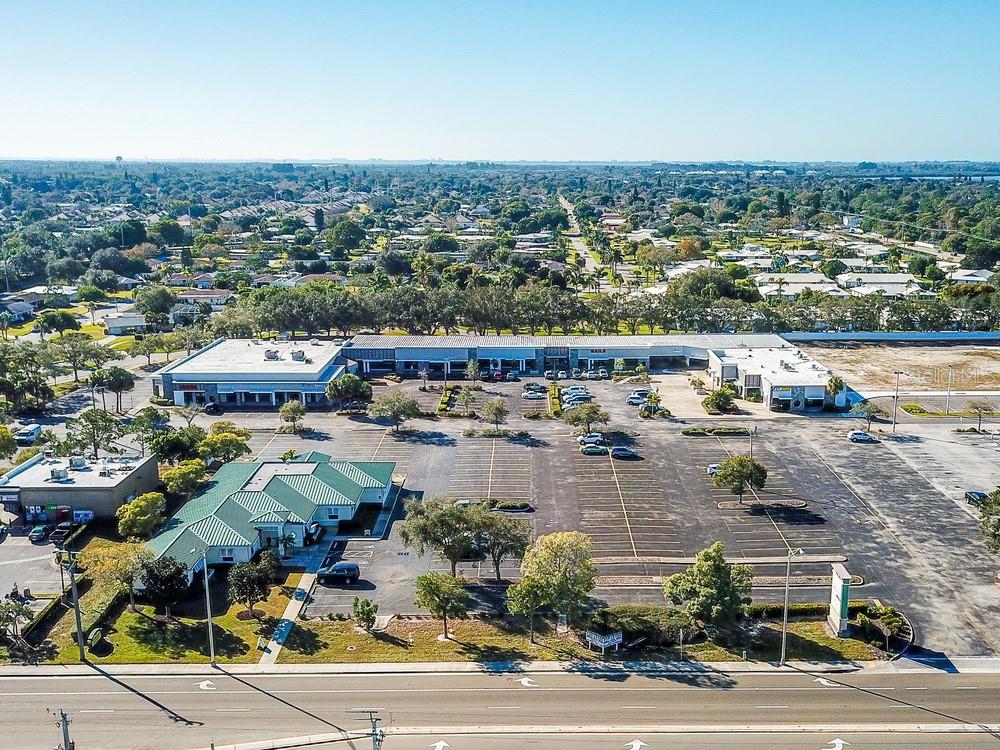 An aerial view of a commercial shopping center with a large parking lot and surrounding neighborhood — 7421 MANATEE AVENUE W UNIT 7437, BRADENTON, FL