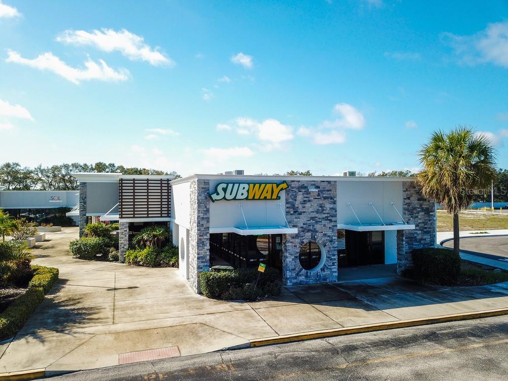 An exterior view of a Subway restaurant building featuring stone veneer accents and a palm tree — 7421 MANATEE AVENUE W UNIT 7437, BRADENTON, FL