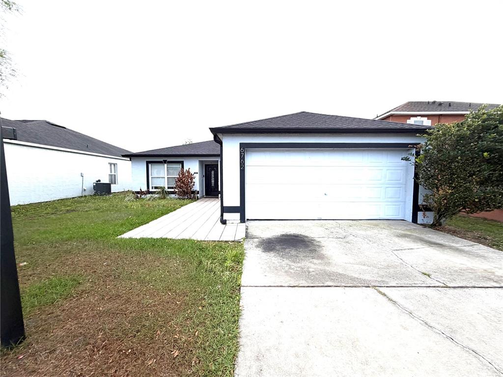 A single-story house with a white garage door, a paved walkway, and a dark roof — 6762 POMEROY CIRCLE, ORLANDO, FL