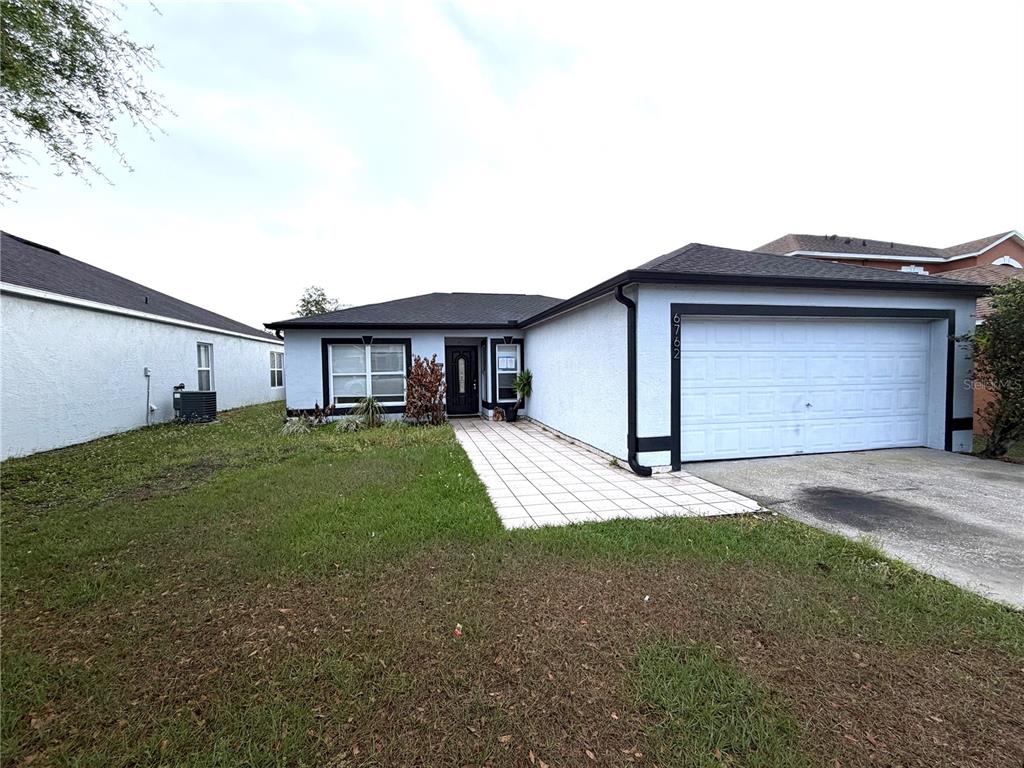 A single-story house with a white stucco exterior, a tiled walkway, and a two-car garage — 6762 POMEROY CIRCLE, ORLANDO, FL